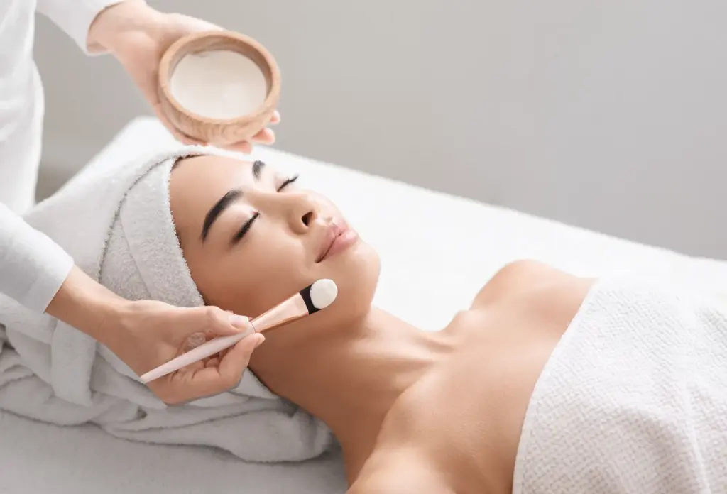 Woman receiving facial treatment with mask application, representing acne treatment and professional skincare service.